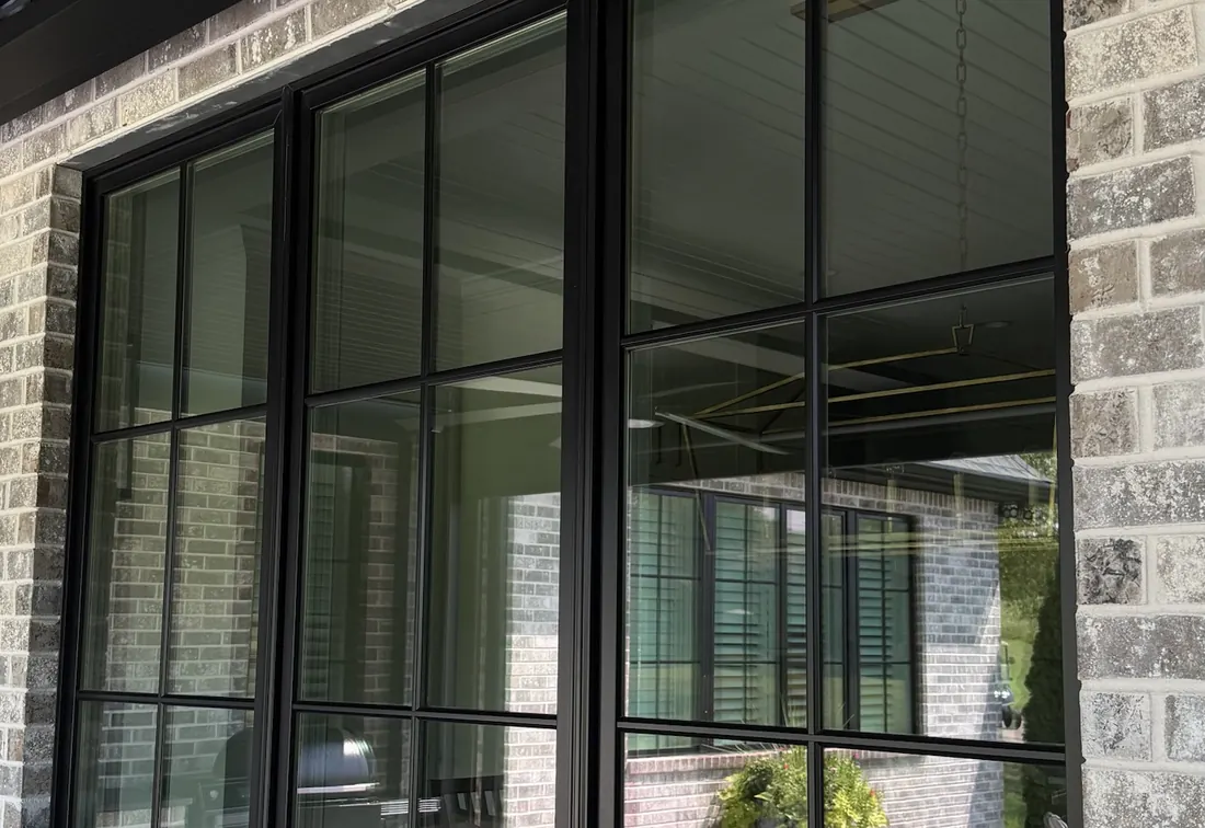 Spotless black-framed windows on a gray brick home after Lucent window cleaning